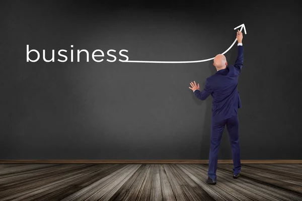 Businessman in front of a wall writing the word business with a — Stock Photo, Image