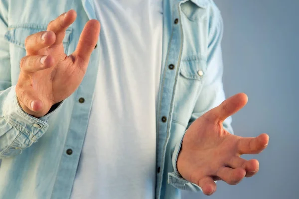 Ung man ger en tom hand på en färgbakgrund — Stockfoto