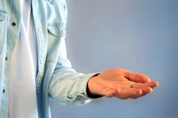 Giovane uomo che dà una mano vuota su uno sfondo di colore — Foto Stock