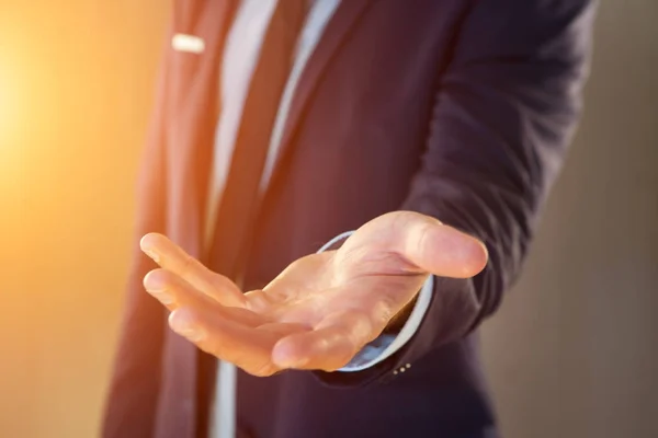 Empresario dando una mano vacía sobre un fondo de color — Foto de Stock