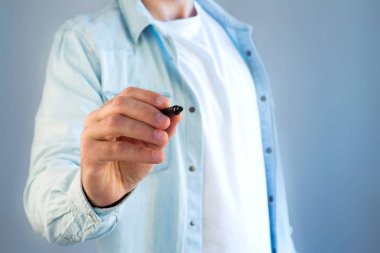 Genç bir adam bir kalemle gri duvarda yazılı görünümünü