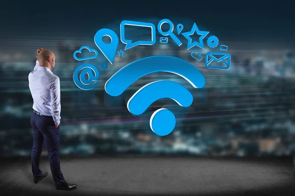 マルチ メディアとインターネット アプリケーションのロゴ レンダリングに囲まれたシンボル Wifi が付いている壁の前で実業家のビュー — ストック写真