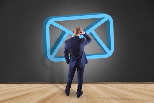 Podnikatel před zdí se symbolem modré Email zobrazen — Stock fotografie