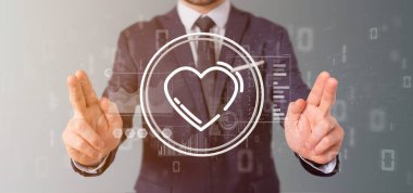 Veri ile çevrili bir kalp simgesi tutan işadamı