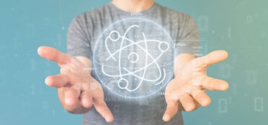 Veri ile çevrili bir atom simgesi tutan işadamı