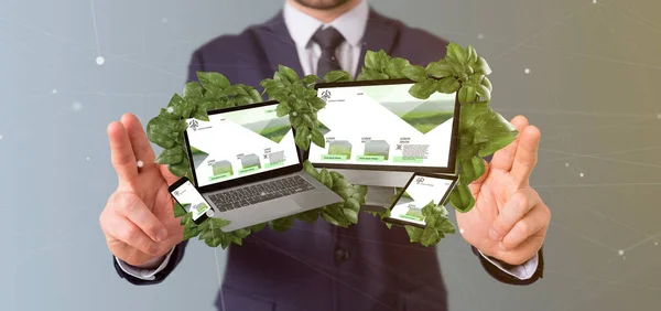 Businessman holding a Connected devices surrounding by leaves 3d
