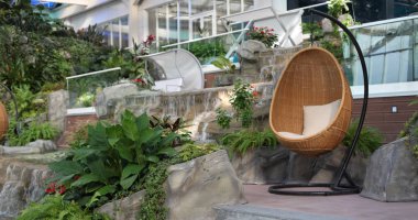 Rattan oval sallanan sandalye tropikal bitkide yastıkla