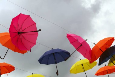 Gökyüzü arka planında sarı, pembe, mavi ve kırmızı şemsiyeler.