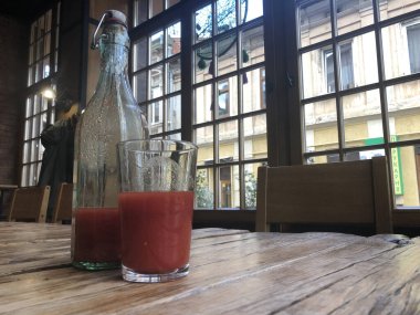 Şişede ev yapımı domates suyu ve kafedeki kaba ahşap bir masada cam..