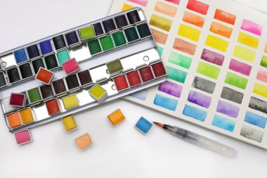 Açık bir kopya alanı üzerinde suluboya, fırça ve palet içeren kutu