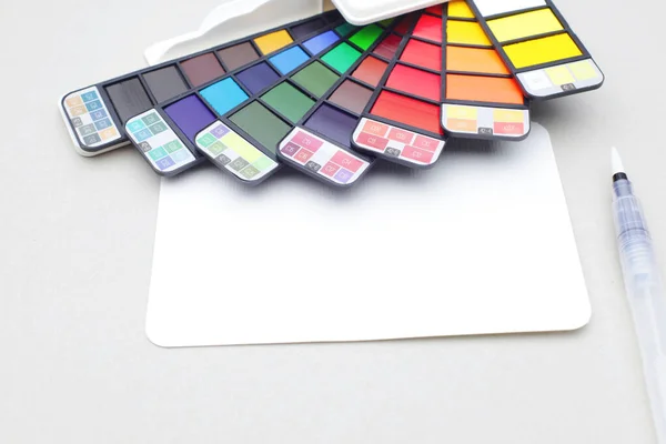 Pudełko Farb Akwarelowych Tęczową Paletą Pędzlem Pustą Kartką Białym Papierze — Zdjęcie stockowe