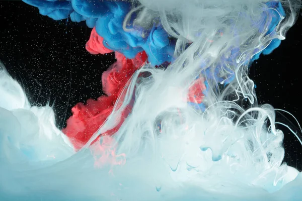 Suda akrilik mavi ve kırmızı renkler. Mürekkep lekesi. Soyut siyah arkaplan. 