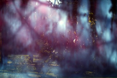 Mistik yansıması olan eski, tozlu bir pencere camı. Yumuşak odaklanma. Çizikli soyut bir arkaplan. Mavi ve morumsu. Işık efekti.