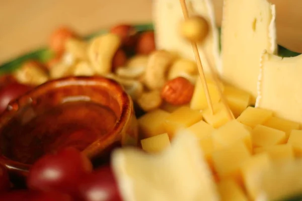 Peynir tabağı. Parmesan peyniri, beyaz küflü peynir, fındık, fındık, kırmızı üzüm ve ıhlamur balı.