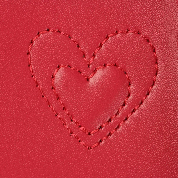 Embroidery in shape of two hearts(small and big) on pink leather — Stock Photo, Image