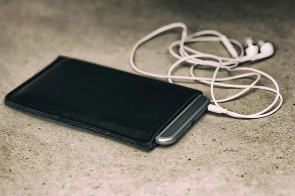 Zwarte case voor smartphone en witte koptelefoon, zijaanzicht, sluiten — Stockfoto