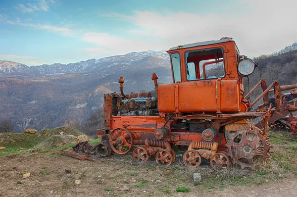 Velho trator enferrujado no fundo das montanhas — Fotografia de Stock