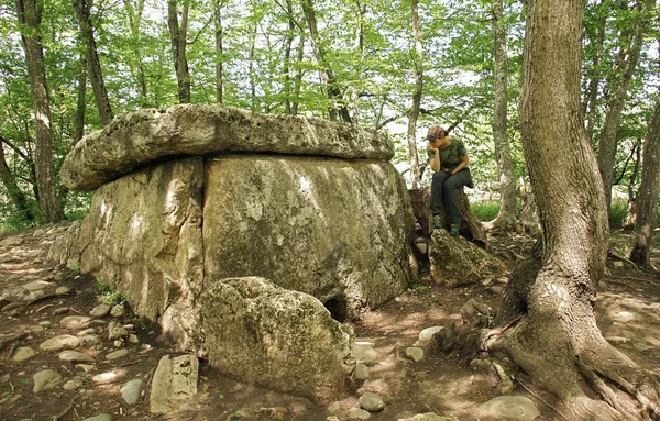 Podróżnik dziewczyna siedzi w pobliżu starożytne dolmeny megalitycznych — Zdjęcie stockowe