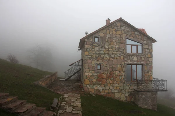 Solitaria casa de piedra en la colina en la niebla, vista lateral — Foto de Stock