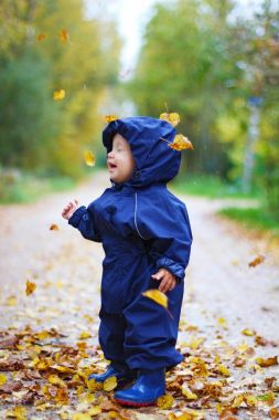 mavi elbiseli bir bebeğe düşen sonbahar yaprakları  