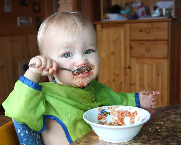 Ребенок ест ложкой квиноа с овощами — стоковое фото