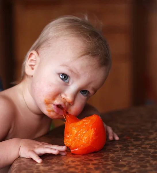 Baby eats fresh ripe persimmon — Stock Photo, Image