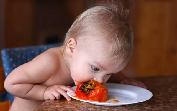 Ребенок ест свежую спелую хурму на белой тарелке — стоковое фото