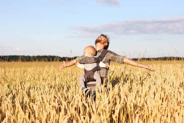 Padre con bebé en cabestrillo en el campo de la cebada — Foto de Stock