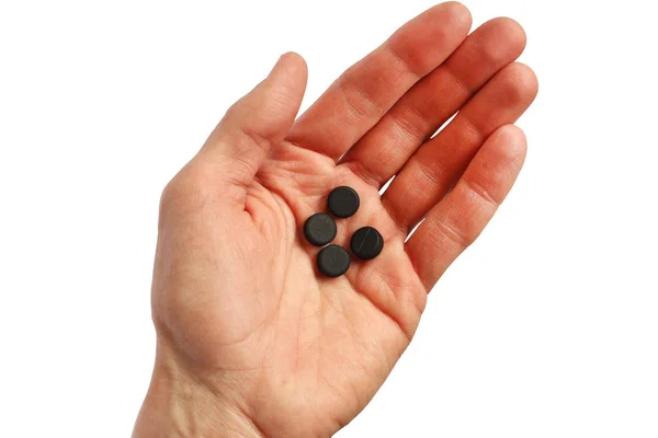 Four black pills in the human palm, isolated — Stock Photo, Image