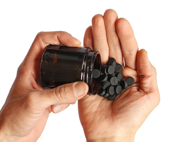 Human pours from the bottle black pills on the palm, isolated — Stock Photo, Image