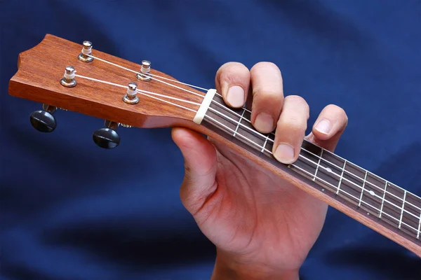 De snaar van de klemmen van de linker musicus hand op de ukulele, zijaanzicht — Stockfoto