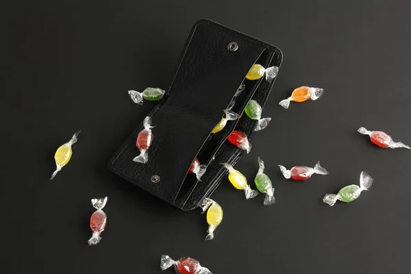 Nyitott fekete pénztárca sok színes cukorka, lapos feküdt sötét háttér, koncepció a költőpénz vagy leértékelés — Stock Fotó