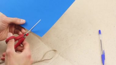 man tries to cut something out of blue paper with red scissors, make some craft work, but does not dare to do it, concept of indecision and hesitation or doubts, torment of creativity 