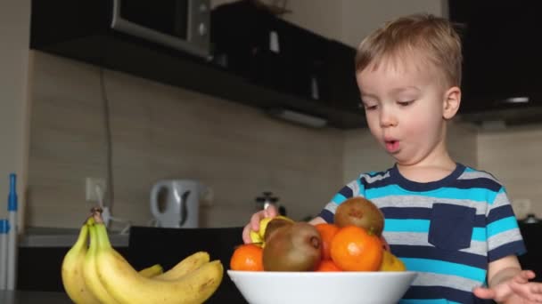 Piccolo Bambino Vegano Guarda Sul Piatto Con Frutta Fresca Felice — Video Stock