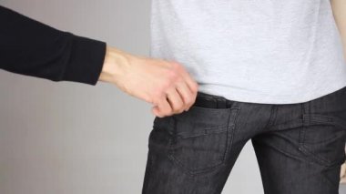 Yankesiciler, siyah pantolonlardan birinin arka cebinden nazikçe deri cüzdan çıkarır. Yankesicilik, hırsızlık, yakın plan.