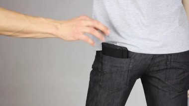 Yankesicilik yapan biri pantolonun arka cebinden siyah deri cüzdan çalmaya çalışır, ama hukukun eli kelepçelenir, el korku içinde titrer, suç işlerken yakalanır, suç ve ceza, yakın plan.  