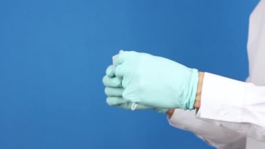 Ellerindeki ameliyat eldivenlerine yan bakış, tıbbi maskeyi göster ve tak, virüs koronavirüsünün önlenmesi veya korunması veya kirliliği, doktor ya da hasta göstergesi, mavi arka plan 