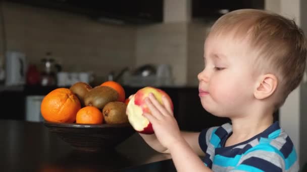 小可爱的素食主义者小孩咬苹果 咀嚼并吃掉 素食主义者小孩在厨房里吃着新鲜的水果 健康的食物富含维生素作为早餐 — 图库视频影像