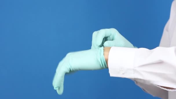 人类的手摘除蓝色外科医用手套 并将其扔进垃圾箱 侧视镜 蓝色背景 病毒或珊瑚流行病的概念结束或完成污染检疫 — 图库视频影像