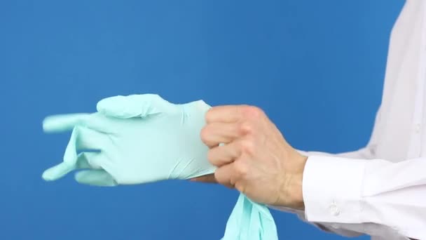 从侧面看人的手 戴上外科或医用手套 预防或保护病毒 医生或病人示范 蓝色背景 — 图库视频影像