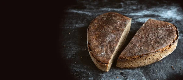 ローフライ麦全粒酵母のないソース生地のパンの形で心の半分にカット スパイスと黒のテーブルの上に 白小麦粉 手作りベジタリアン健康有機素朴なパン プライベートベーカリー コピースペース — ストック写真