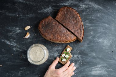 Isırılmış sandviç, soğan soğanı ve sarımsaklı ekmek, ekşi hamurlu cam kavanoz, vejetaryen çavdar ekmeği, mayasız ekmek, mayasız ekmek, kalp, üst manzara, mütevazı yemek tatma. 