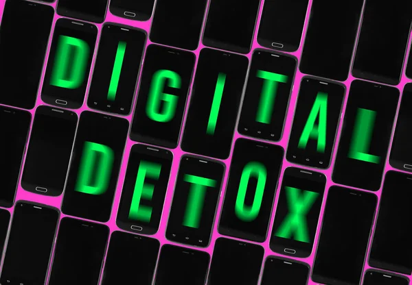 different off black smartphones with green blurred text digital detox on screens, tilted words, pink background