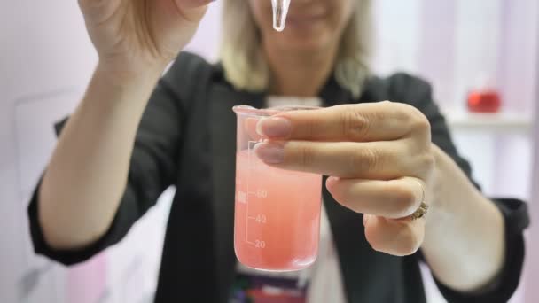 Fêmea química derramando óleo cosmético no líquido de teste, produção de cuidados com o corpo . — Vídeo de Stock