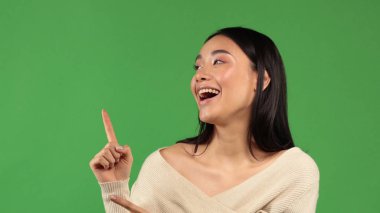 Aktif genç Asyalı kadın işaret parmağını kaldırıp yan tarafa bakıyor ve gülümsüyor.