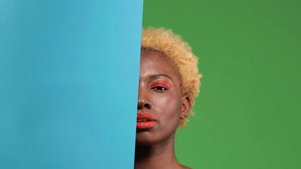 Afro-américain avec demi-visage de maquillage lumineux recouvert de papier bleu — Photo