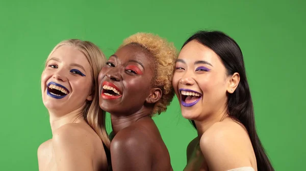 Internationella kvinnor ler mot halvvägs makeup med europeiska, asiatiska och afroamerikanska kvinnor med flerfärgad makeup — Stockfoto