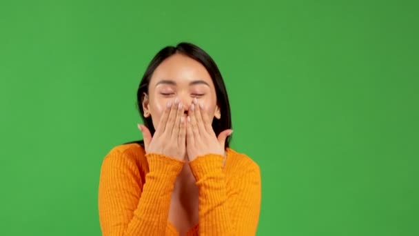 Радостная азиатская молодая девушка с энтузиазмом двумя руками дует поцелуем и улыбками, концепцией радости удовольствия и хорошего настроения — стоковое видео