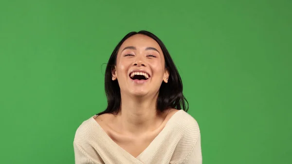 Красивая молодая веселая веселая азиатка счастливо улыбается в фотоаппарат с естественным тоном кожи с минимальным количеством макияжа на лице. Концепция позитивного настроения, настроение радости, веселья — стоковое фото