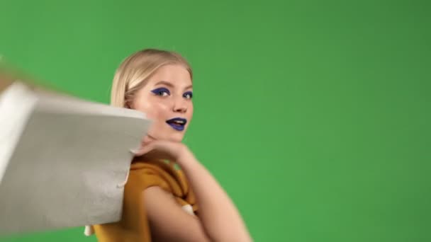 Giovane donna bionda con trucco luminoso tiene pacchetti colorati nelle mani del negozio, shopping e intrattenimento concetto — Video Stock